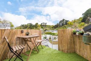 a patio with a table and chairs and a fence at Face a la mer avec terrasse ensoleillee Brehec in Plouha