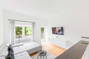a white living room with a white couch and a tv at Kingsize Bett, Terrasse, Netflix, zwei Zimmer in Pforzheim