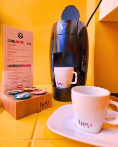 eine Kaffeemaschine und zwei Tassen auf dem Tisch in der Unterkunft Andar de Cima Suítes in São Paulo