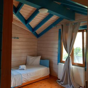ein Schlafzimmer mit einem Bett in einem Zimmer mit einem Fenster in der Unterkunft WOODEN HOUSE in Preveza
