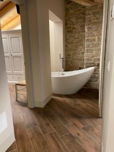 a white tub in a bathroom with a stone wall at Albergo del Bramante in Roccaverano