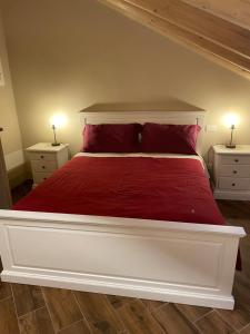 a bedroom with a large bed with red sheets and pillows at Albergo del Bramante in Roccaverano