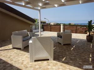 - une terrasse avec 2 chaises et un parasol dans l'établissement FAVARA Rooms, à Portopalo di Capo Passero