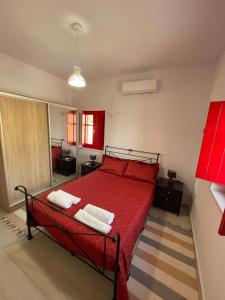 een slaapkamer met een rood bed en handdoeken erop bij Sugar Stone House 2 in Pirgos Dhirou