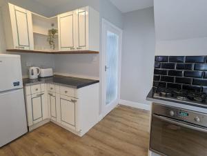 a kitchen with white cabinets and a stove top oven at Alexander Apartments High Heaton in Gosforth