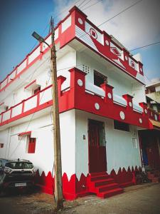 ein rot-weißes Gebäude mit einem Auto, das vorne geparkt ist in der Unterkunft John Beach House in Puducherry