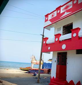 - un bâtiment rouge avec un cheval sur la plage dans l'établissement John Beach House, à Pondichéry