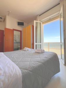 a bedroom with a large bed with a large window at Hotel Carnaby in Rimini