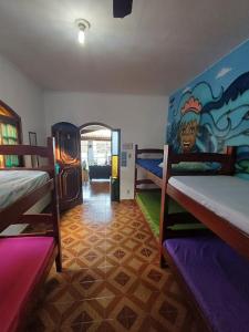 a room with two bunk beds and a painting on the wall at Hostel do Valdemar in Praia Grande