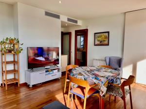 een woonkamer met een tafel en een televisie bij Claire perfect vilanova penthouse by hlclub agency in Vilanova i la Geltrú
