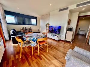 ein Wohnzimmer mit einem Tisch und einem TV in der Unterkunft Claire perfect vilanova penthouse by hlclub agency in Vilanova i la Geltrú