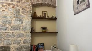 a hallway with a stone wall with a shelf and books at Apartment Kova in Split