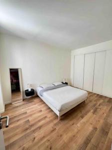 una camera bianca con letto e pavimento in legno di Le petit Marseillais a Marsiglia