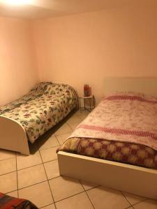 a bedroom with two beds and a tiled floor at Dar nour in Les Abrets en Dauphine