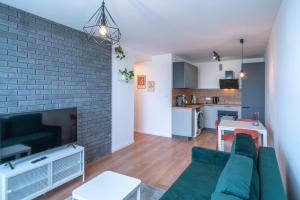 a living room with a green couch and a brick wall at Verde Apartment SelfCheck-in 24h in Wrocław