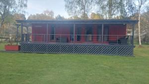 ein rotes Gebäude mit einer Veranda auf einem Feld in der Unterkunft Pids randõ in Kolka