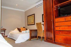 a bedroom with a bed and a dresser at RIETONDALE LODGE in Pretoria