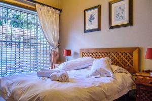 Un dormitorio con una cama blanca con toallas. en RIETONDALE LODGE en Pretoria