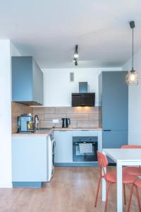 a kitchen with blue cabinets and a table and chairs at Verde Apartment SelfCheck-in 24h in Wrocław