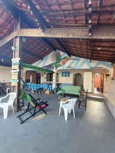 an outdoor patio with white chairs and a couch at Hostel do Valdemar in Praia Grande