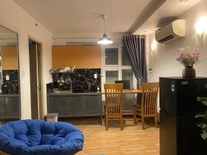 a living room with a blue ottoman and a kitchen at CHILL HOME 2 in Ho Chi Minh City