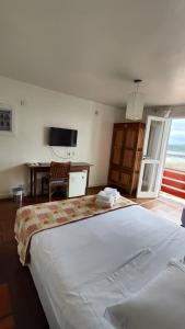 a bedroom with a large white bed and a desk at Hotel Camboa Antonina - PR in Antonina