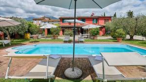 a swimming pool with two chairs and an umbrella at Casa Rocchi in Capannori