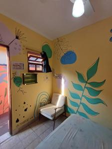 a room with a chair and a wall with drawings on it at Hostel do Valdemar in Praia Grande