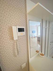 Like Home Hostel na Shevchenko, 162Б في ألماتي: حمام مع تلفزيون على جدار مع مرآة