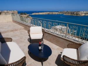 Un balcón con sillas, una mesa y el océano en Battery House en La Valeta