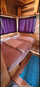 Cama en habitación con cortinas moradas en Nap kemping 84 parcella en Fonyód