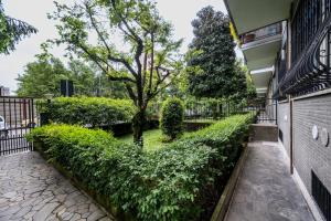 a hedge in front of a building with a tree at Airguest Pianella Rooms in Milan