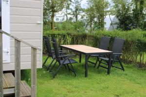 a table and chairs in the grass next to a house at Minicamping Zonnehoek in Biggekerke