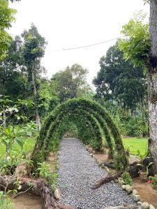 an archway in a garden with a gravel road at Wisma Batu Mandi and offers jungle tours in Bukit Lawang