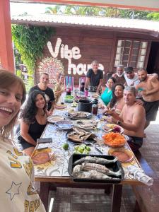 um grupo de pessoas sentadas à volta de uma mesa com comida em Vibe House Hostel em Florianópolis