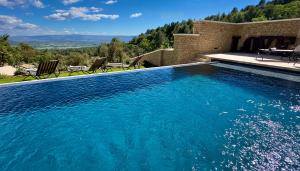 una piscina con agua azul frente a una casa en Mas La Rose Sauvage - magnificent Luberon views, en Murs
