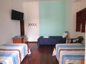 Kleines Zimmer mit 2 Betten und einem TV in der Unterkunft Hotel Casita de Belén in Sonsón