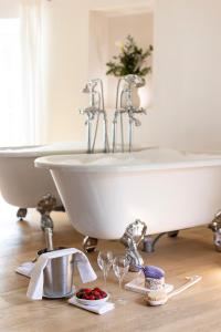 a white bath tub sitting in a bathroom with wine glasses at Château Les Oliviers de Salettes in Charols
