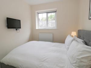a bedroom with a white bed with a tv on the wall at The Old Stables in Ruthin