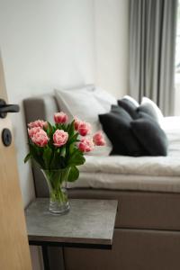 a vase of pink flowers on a table next to a bed at Private House with 4 Bedrooms and SAUNA near TARTU 