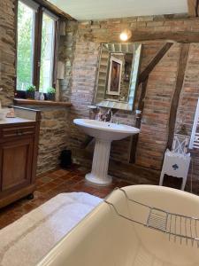 une salle de bain avec un lavabo, une baignoire et un miroir dans l'établissement Cottage chez Emilie, à Beaulieu
