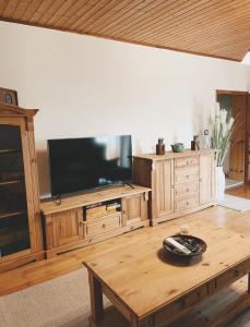 een woonkamer met een televisie en een houten tafel bij Uriges Bauernhaus mit Blick auf Graz in Graz