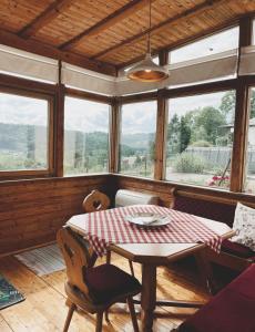 ein Esszimmer mit einem Tisch und einigen Fenstern in der Unterkunft Uriges Bauernhaus mit Blick auf Graz in Graz