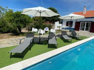 a group of chairs and an umbrella next to a swimming pool at Ferroa Guest House in Cano