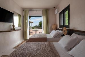 a hotel room with two beds and a balcony at Kynthia Hotel - Adults Only in Kalogria