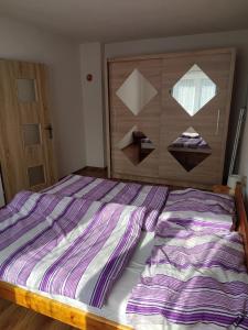 Dormitorio con cama de rayas púrpura y blanca en Privat ZUZANA, en Prosiek