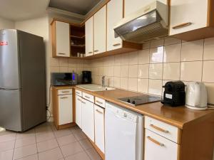 a kitchen with a stainless steel refrigerator and white cabinets at L'appartement des Champs Elysées in Paris