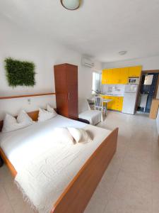 a bedroom with a large bed and a kitchen at Apartmani Barešić in Podgora