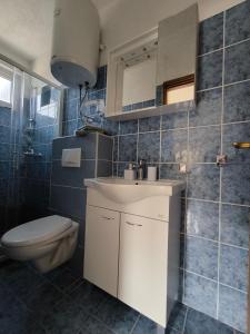 a bathroom with a white sink and a toilet at Apartmani Barešić in Podgora +103 photos