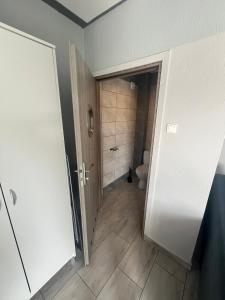 a bathroom with a toilet and a door to a room at Nemo - apartament, domek w Gaskach in Gąski